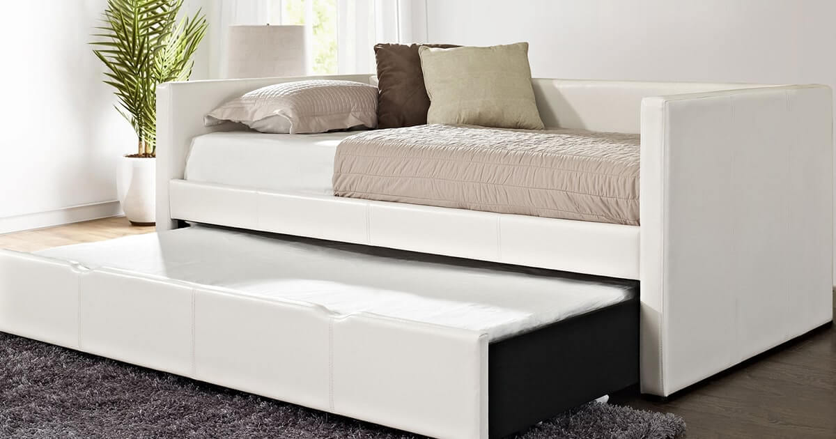 A stylish white leather daybed surrounded by potted plants in a cozy living room setting.