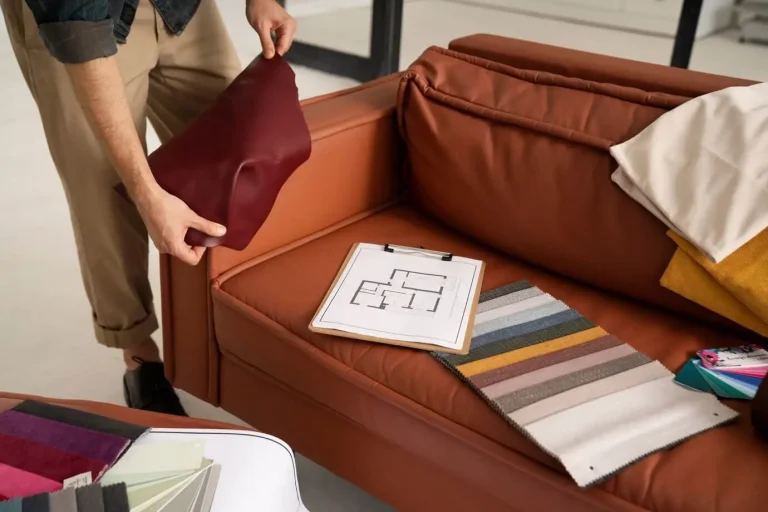 Man on a couch, holding a fabric sample, engaged in the process of selecting materials