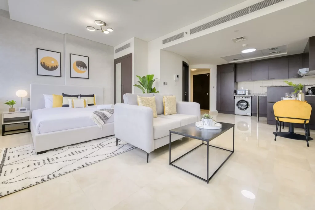 Interior view of a modern studio apartment highlighting a stylish kitchen connected to a cozy living room and a bedroom