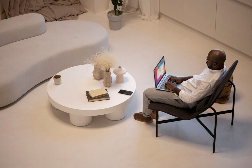 A man comfortably sitting on a chair, using a laptop for work or personal tasks.