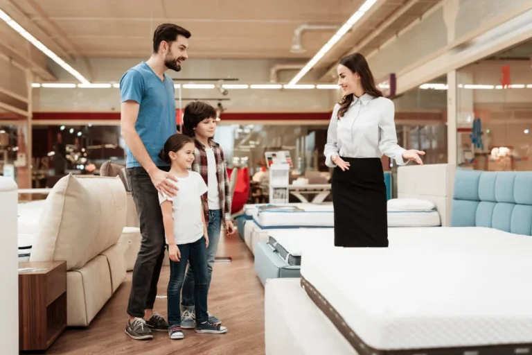 A family examines various mattresses in a store, discussing options and comparing features together.